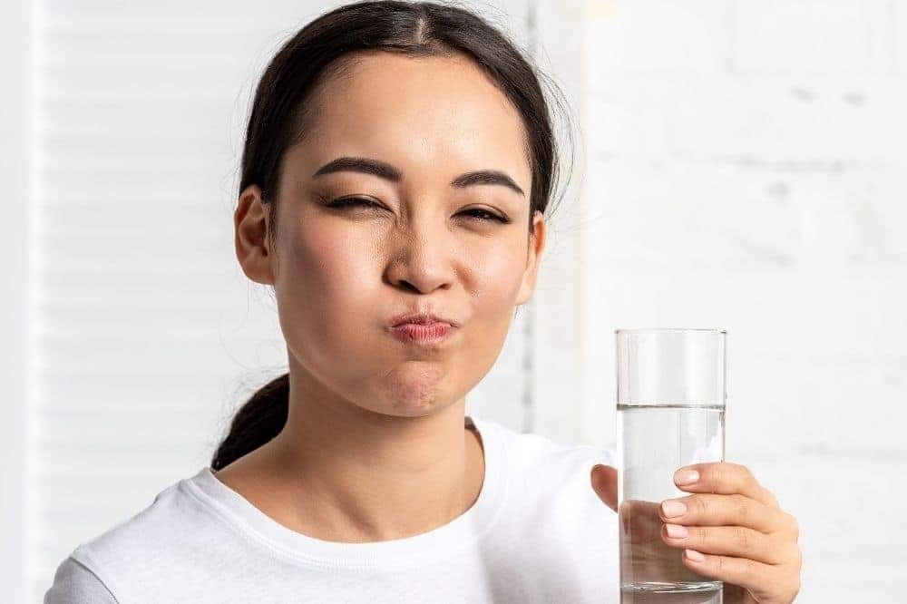 Niềng răng có đau không? Giai đoạn nào đau nhất 5 Cô gái đang súc miệng bằng nước muối ấm để làm sạch khoang miệng và giảm đau nướu.
