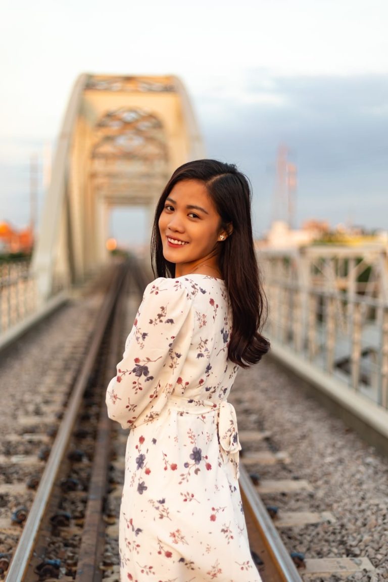 smiling vietnamese woman with black hair standing old bridge